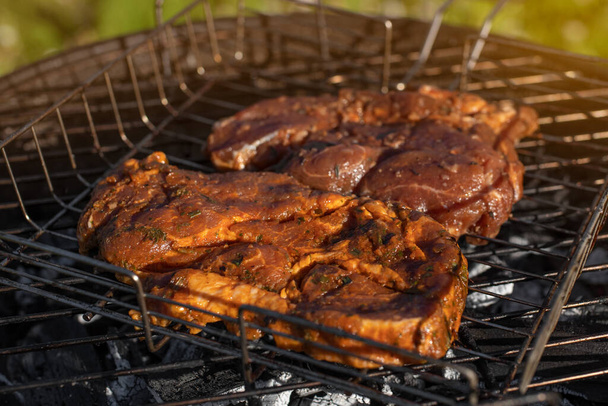 グリルで味付けされた豚肉の眺め。バーベキューグリルの外で肉を焼く。夏の屋外グリルパーティー。夏の晴れた日.  - 写真・画像