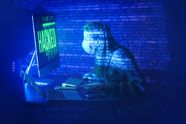 Mulher sentada perto do computador hackeado no quarto escuro - Foto, Imagem