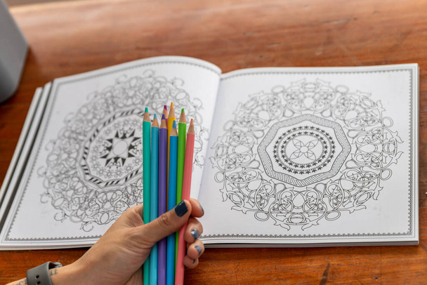 a handful of colored pencils and a book of mandalas for coloring - Photo, Image