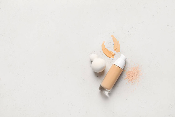 Makeup sponge with tonal foundation and powder on grey background - Foto, imagen