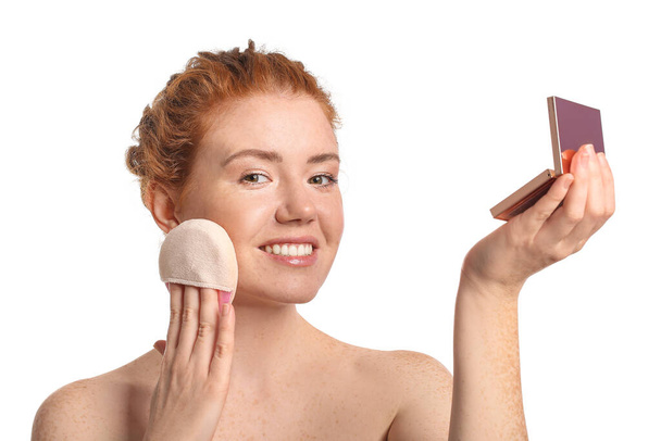 Beautiful young woman with makeup sponge and cosmetics on white background - Φωτογραφία, εικόνα