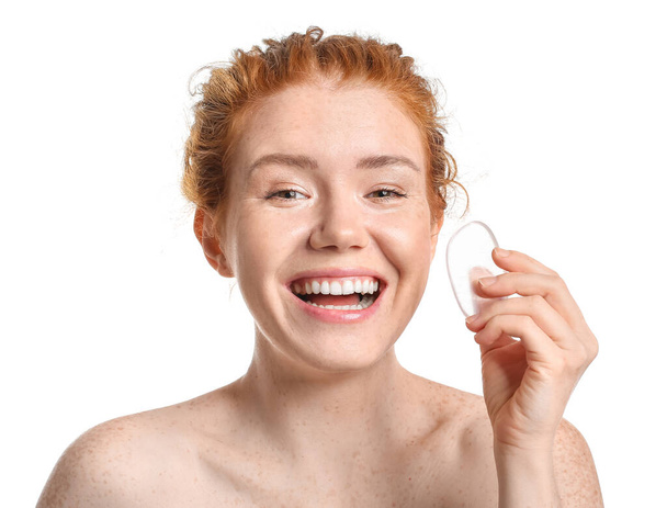 Όμορφη νεαρή γυναίκα με σφουγγάρι μακιγιάζ σε λευκό φόντο - Φωτογραφία, εικόνα