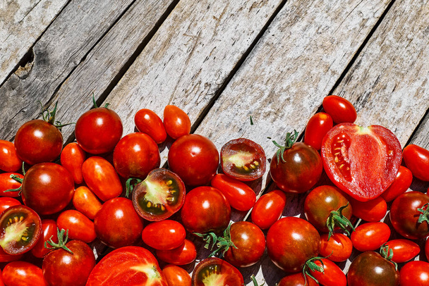 Kırmızı olgun domates dokusu arka planı. Tahta masadaki domateslerin farklı özellikleri. Siyah domates Solanum lycopersicum. - Fotoğraf, Görsel