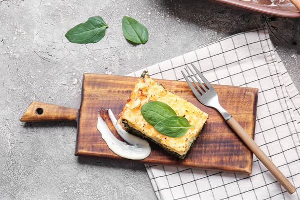 Board with tasty green lasagna on grunge background - Фото, изображение