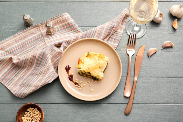 Plate with tasty green lasagna and glass of wine on wooden background - Zdjęcie, obraz