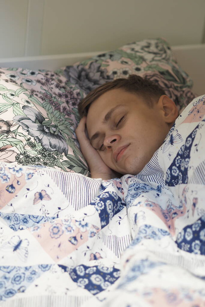 A young man sleeps in bed under a blanket. High quality photo - Photo, image