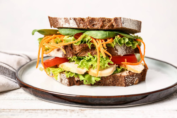 Plate with tasty sandwich on light wooden table, closeup - Photo, image