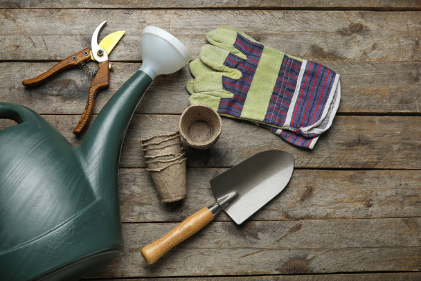 Lata de riego, macetas de turba y herramientas de jardinería sobre fondo de madera - Foto, Imagen