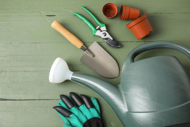Regadera, macetas y herramientas de jardinería sobre fondo de madera de color - Foto, imagen
