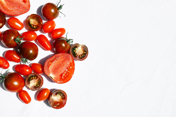 Kırmızı olgun domates dokusu arka planı. Beyaz keten masa örtüsünün üzerindeki domateslerin farklı nitelikleri. Siyah domates Solanum lycopersicum. - Fotoğraf, Görsel