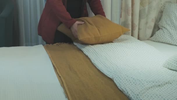Müde nach dem Flug richtet eine Kaukasierin ihr Bett in einem Hotelzimmer auf - Filmmaterial, Video