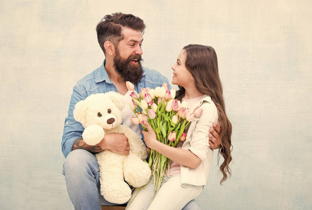 happy holiday. father and daughter with flowers and toy. teen girl and dad hold tulip bouquet. 8 march or womens day. spring holiday gift. love and family values. happiness. happy family day - Fotografie, Obrázek