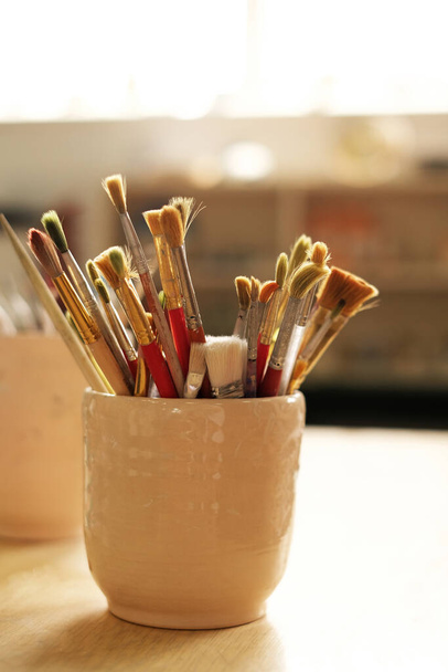 vaso con pennelli sul desktop. master class in pittura e ceramica. laboratorio creativo - Foto, immagini