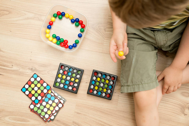 Childs hand on colorful wooden marbles. Color sequence logic game. A tool for pre-school and primary education. Montessori, brain exercise. Focus, patience and attention practice. - Valokuva, kuva