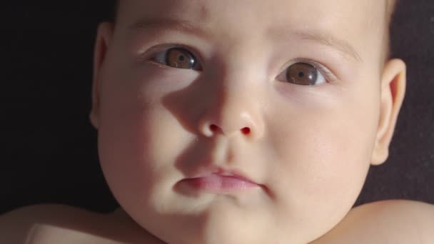カメラの中の赤ん坊の外観を閉じるショット。可愛い赤ちゃんがカメラを見ている。子供の世話、親の愛の概念. - 映像、動画