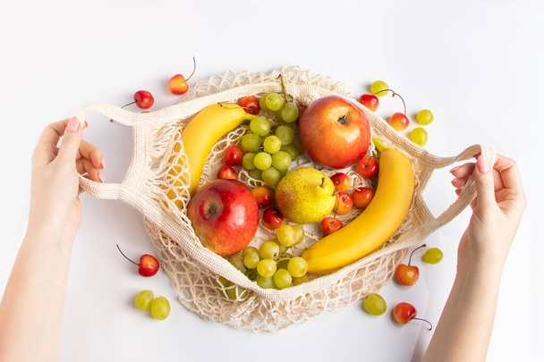 Dłonie kobiet trzymają ekologiczną torebkę z owocami. Organiczne wegańskie jedzenie. Zero odpadów i koncepcja zrównoważonego stylu życia. - Zdjęcie, obraz