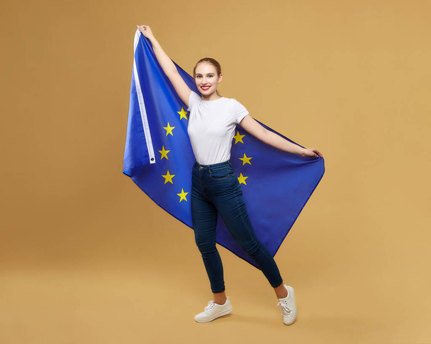 attractive blonde poses with the flag of the European Union. photo shoot in the studio on a yellow background. - Foto, Bild