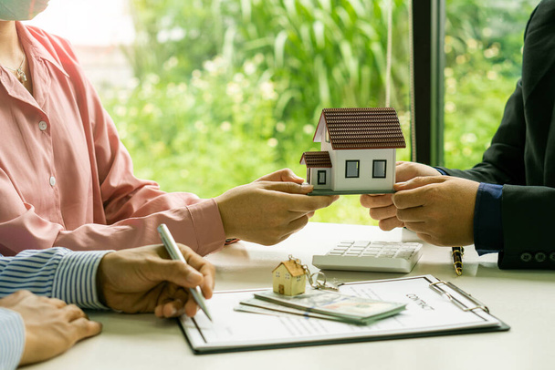 Satıcı ev satın alma sözleşmesi teklif eder veya kredi ve faiz oranlarını tartışır. Yeni ev sahipleri arasında bir ev alırken veya masa, çalışma alanı, ev satın alma ve kiralama fikirleri arasında. - Fotoğraf, Görsel