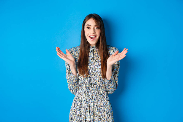 Excited beautiful woman clap hands and congratulate you, praising nice work, applause at camera and smiling, standing on blue background - Photo, Image