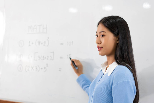 Educational concept a young smart female teacher explaining decision of hard math in a classroom before Covid-19 epidemic. - 写真・画像