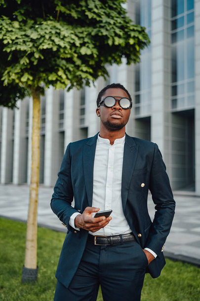 Confident african businessperson weared in suit with phone - Fotó, kép
