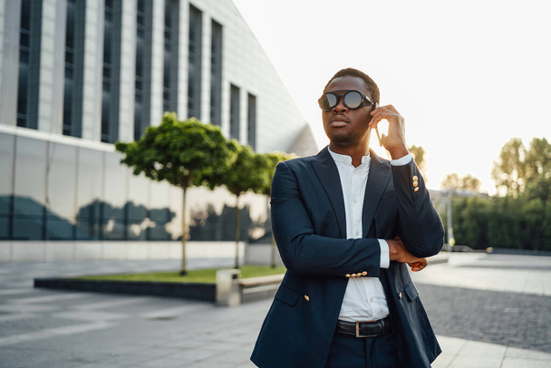 Afrikaanse zakenman in gesprek op zijn telefoon tegen stadsgezicht - Foto, afbeelding