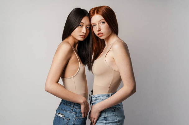 Multiracial two women posing and looking at camera isolated over white wall - Foto, Imagem