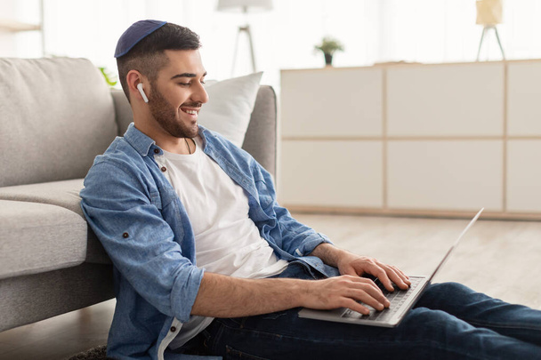 Jovem israelita do sexo masculino em kippa trabalhando no laptop em casa - Foto, Imagem