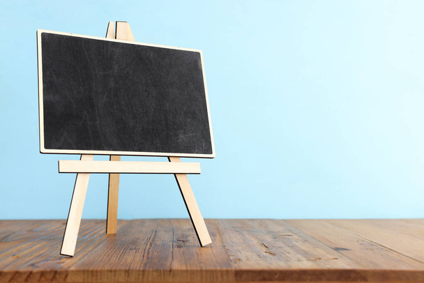 empty small blackboard over blue wooden background - 写真・画像