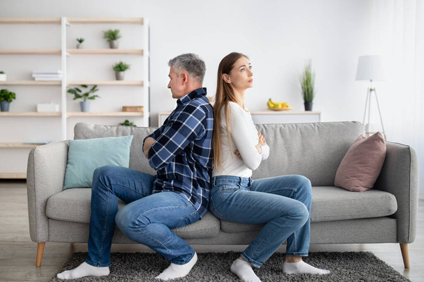Ehepaar mittleren Alters sitzt Rücken an Rücken auf der Couch und spricht nach Konflikten zu Hause nicht miteinander - Foto, Bild