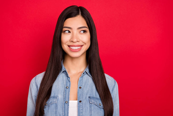 Photo of young attractive asian girl happy positive smile curious look empty space isolated over red color background - Foto, Imagen