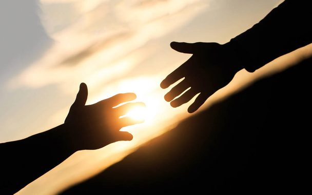 Friendly handshake, friends greeting, teamwork, friendship. The outstretched hands, salvation, help silhouette, concept of help. Giving a helping hand. Rescue, helping gesture or hands - Photo, Image