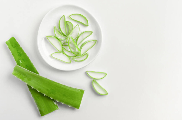 Foglie verdi e fette di aloe vera su un piatto bianco. Copia spazio. - Foto, immagini