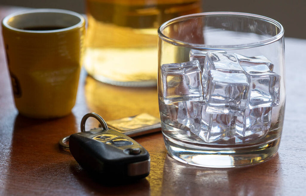 テーブルの上に氷と車のキーとウィスキーのグラスでアルコール乱用. - 写真・画像