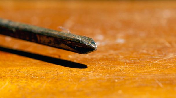 Nahaufnahme eines rostigen Schraubendrehers auf einem braunen Tisch, ausgewählter Fokus - Foto, Bild