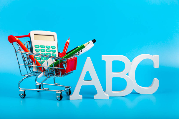 ABC letters, stationery and shopping cart on a blue background. Shopping for school. Back to school. - Foto, immagini