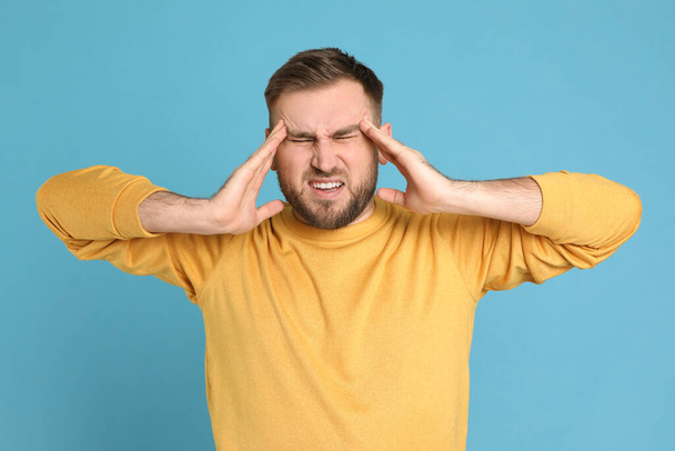 Man suffering from migraine on light blue background - Photo, image