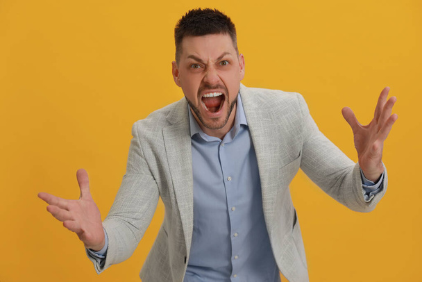 Angry man yelling on yellow background. Hate concept - Foto, Imagem