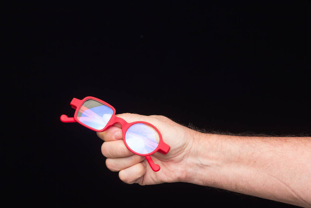 Moderne Brille, Rezept, auf schwarzem Hintergrund, in der Hand einer erwachsenen Person - Foto, Bild
