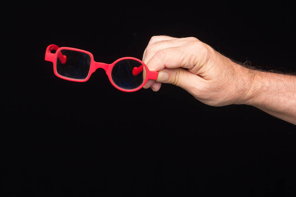 Moderne bril, recept, op een zwarte achtergrond, in de hand van een volwassene - Foto, afbeelding