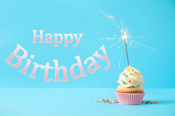 Happy Birthday! Delicious cupcake with sparkler on light blue background  - Zdjęcie, obraz