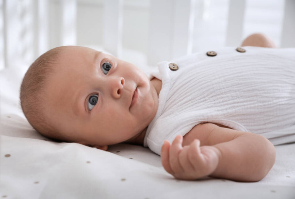 Cute little baby lying on bed at home, closeup - Foto, Imagen