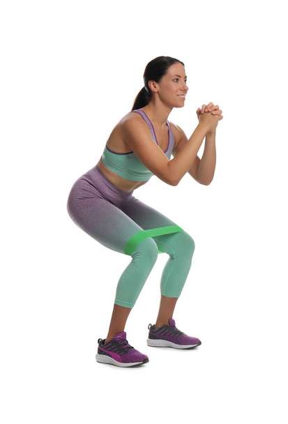 Woman doing squats with fitness elastic band on white background - Foto, immagini