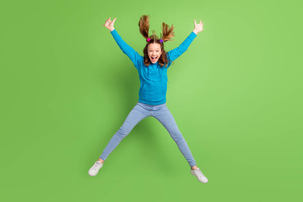 Full length photo of crazy happy girl jump up raise hands fly hair active isolated on green color background - Foto, afbeelding