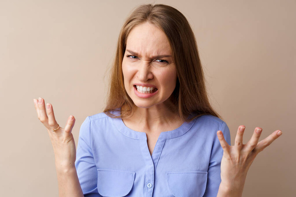 Angry stressed mad young woman against beige background - Foto, Imagen