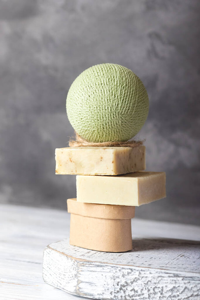 Jabón hecho a mano sobre podio de madera blanco sobre fondo de hormigón - Foto, Imagen