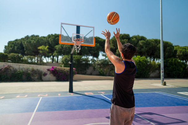 Male sportsman playing basketball throwing the ball at playgroun - Photo, Image