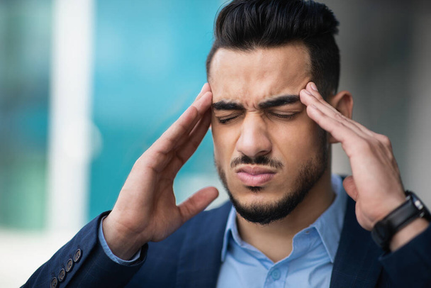 Gestresste jonge Arabische zakenman lijdt aan hoofdpijn - Foto, afbeelding