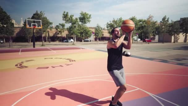 basketbalspeler op het basketbalveld gooit de bal in de basket, en na een misser wordt hij boos - Video