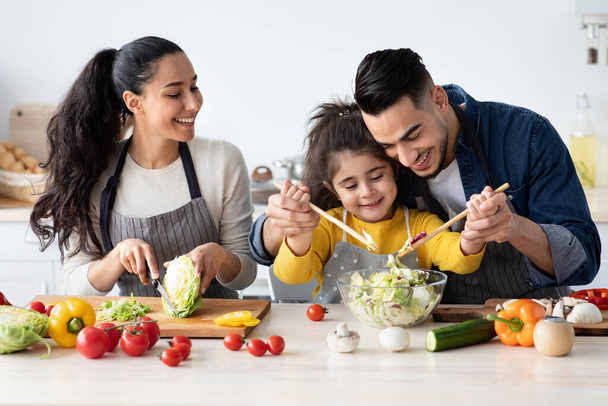Porträt einer fröhlichen jungen arabischen Familie mit süßer kleiner Tochter beim gemeinsamen Kochen - Foto, Bild